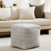 Light gray woven cube pouf made from recycled PET yarn, with a textured finish, in a modern living room.