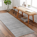 Surya Hickory HCK2303 gray multi-tone hand-loomed recycled PET yarn runner rug on a wood floor.