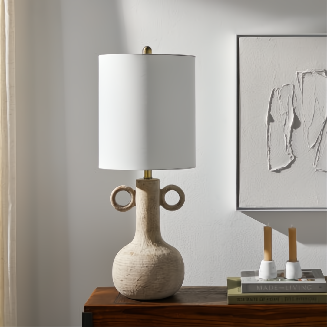 Surya Brava accent table lamp with a textured, light beige vase-like base and a white fabric drum shade.