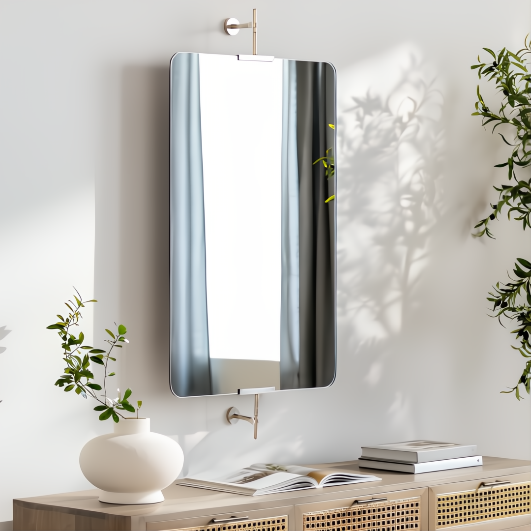 Rectangular mirror with rounded corners, brass frame, and wall-mounted hardware over a wooden console.