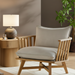 Surya Arco accent chair with light beige linen cushions and a natural wood frame.