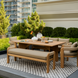 Surya Palma outdoor bench with Sunbrella upholstery and teak wood base, part of a dining set on a patio.