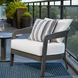 Gray Surya Daniella outdoor accent chair with white cushions and striped throw pillow on a balcony.
