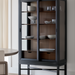 Tall Marin bookcase with black frame, walnut interior, glass doors, and adjustable shelves displaying dishes.