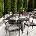 Surya Antibes outdoor dining set with black table and striped Sunbrella chairs on a patio.