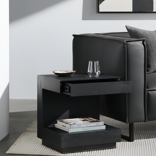 Surya Coburn black mango wood end table with open drawer, glass, and books.