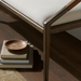 Surya Atra Bench with light beige upholstered cover, brown red oak base, and leather cord wrap detail.