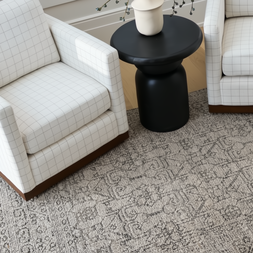 Surya Koben black mango wood end table with a turned base between two white grid-patterned armchairs.