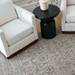 Surya Koben black mango wood end table with a turned base between two white grid-patterned armchairs.