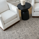 Surya Koben black mango wood end table with a turned base between two white grid-patterned armchairs.