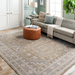 Surya Almeria low pile rug with mustard, gray, pale blue, and beige geometric patterns in a living room.