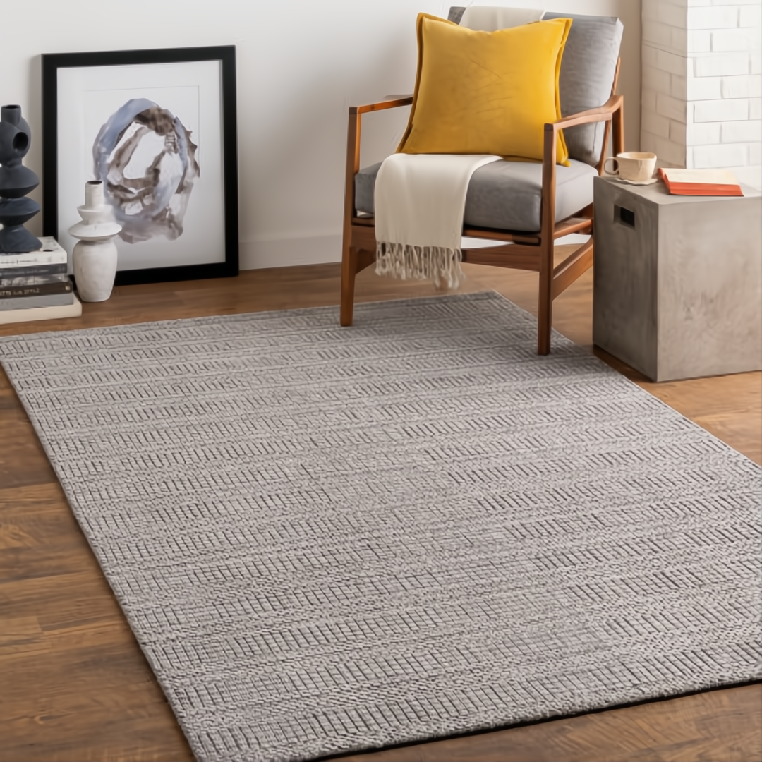Surya Hickory HCK2304 area rug, light gray with subtle chevron pattern, on a wood floor.