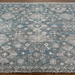 Hand-knotted Surya Almeria rug with a low pile, featuring a distressed teal, gray, and white geometric pattern.