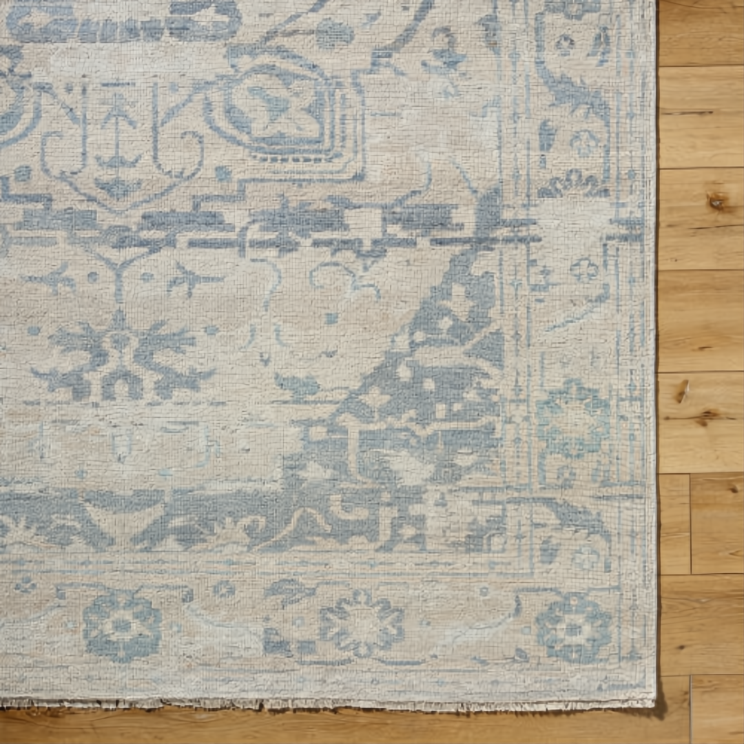 Hand-knotted Surya Cappadocia wool rug with light beige and blue traditional pattern, fringe, on wood floor.