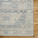 Hand-knotted Surya Cappadocia wool rug with light beige and blue traditional pattern, fringe, on wood floor.