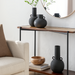 Modern black ceramic decorative accent set with sculptural vase forms on a console table.