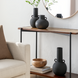Modern black ceramic decorative accent set with sculptural vase forms on a console table.