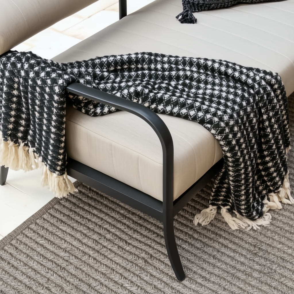 Surya Antibes Loveseat with black aluminum base, beige cushions, and a black and white patterned throw.