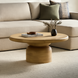 Beige mango wood round coffee table with a brushed finish, featuring a thick top and a cylindrical base.