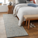 Surya Aiden hand-tufted wool runner rug in light blue and cream, shown in a bedroom.