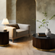 Round Surya Nems coffee table with black marble top, dark brown fluted mango wood base, and gold accents.