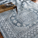 Hand-knotted Surya Almeria low pile area rug in black, gray, beige, and pale blue with geometric patterns.