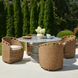 Four Surya Marvella dark brown wicker dining chairs with cream cushions around a gray outdoor table.