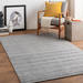 Surya Hickory HCK-2303 gray hand-loomed recycled PET rug with subtle textured stripes in a modern living room.