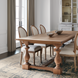 Hand-knotted wool area rug with traditional charcoal, wheat, and taupe design under a wooden dining table.