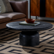 Round black sandblasted mango wood coffee table with a turned base, 36" wide.