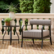 Surya Antibes accent chair with black aluminum frame and striped Sunbrella cushion on a patio.