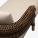 Brown woven armrest of a Surya Porta outdoor sectional with a light beige Sunbrella cushion.