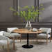 Round Surya Anatalia dining table with a brown acacia top and black iron pedestal base, surrounded by three chairs.