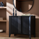 Surya Ronan black mango wood cabinet with ribbed doors, 32"H x 37"W, next to a round mirror.