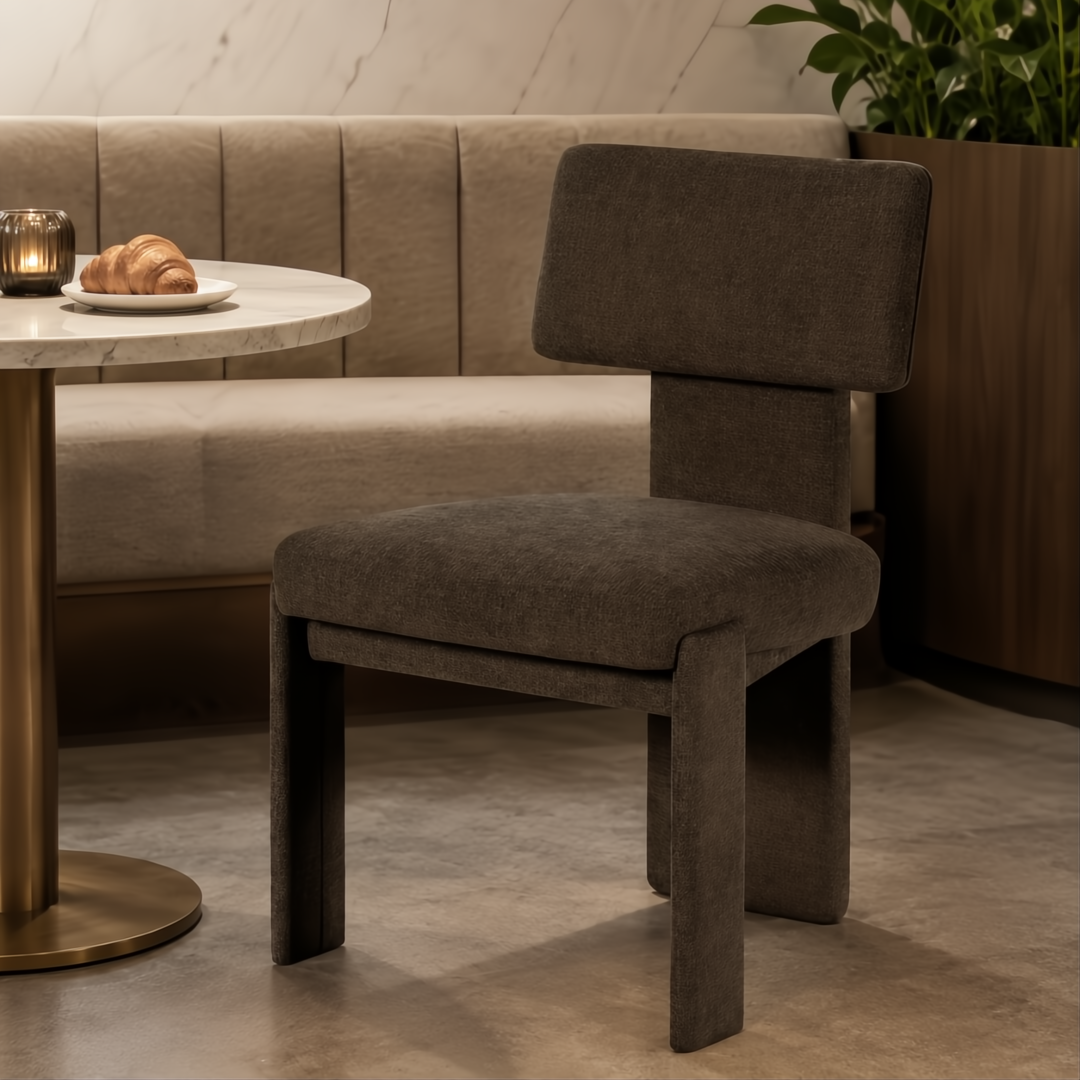 Dark gray upholstered Surya Sitara Dining Chair with a modern design, next to a marble table.
