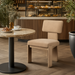 Beige polyester Surya Sitara dining chair with a natural rubber wood base next to a marble table in a cafe setting.