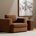 Modern Surya Cahill accent chair in rich brown polyester with a charcoal base, next to a wood side table.