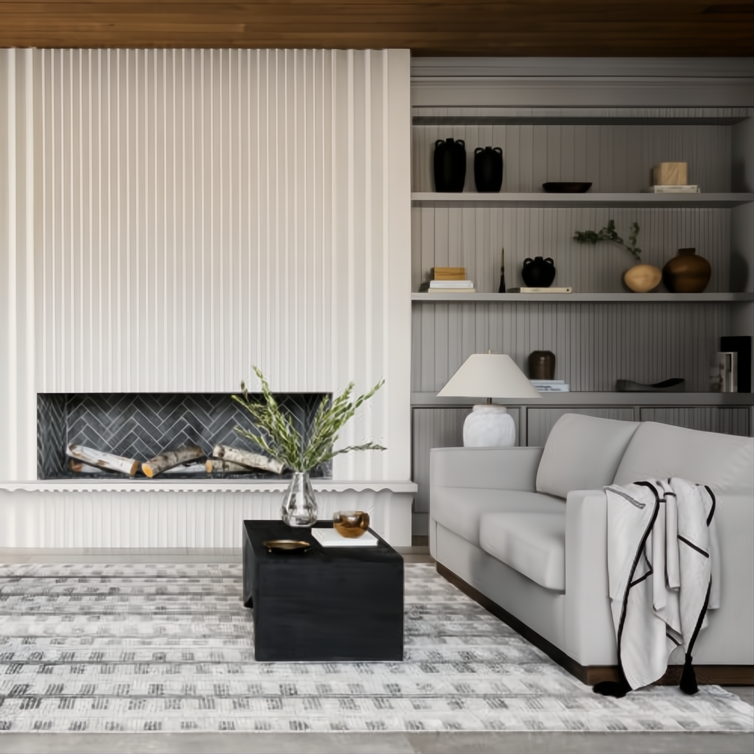 Modern living room with a white fluted fireplace, gray sofa, black coffee table, and decorative ceramic accents.