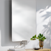 Modern rectangular mirror with rounded corners, mounted above a light wood console table with a plant.