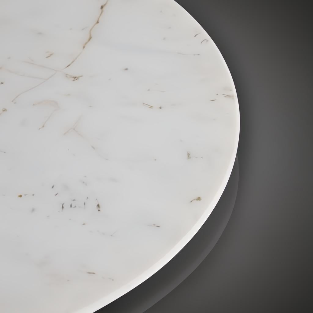 Denali Accent Table with a round white marble top and subtle brown veining, against a dark background.
