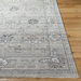 Surya Almeria low pile area rug in medium gray, gray, and cream with refined decorative fringe.