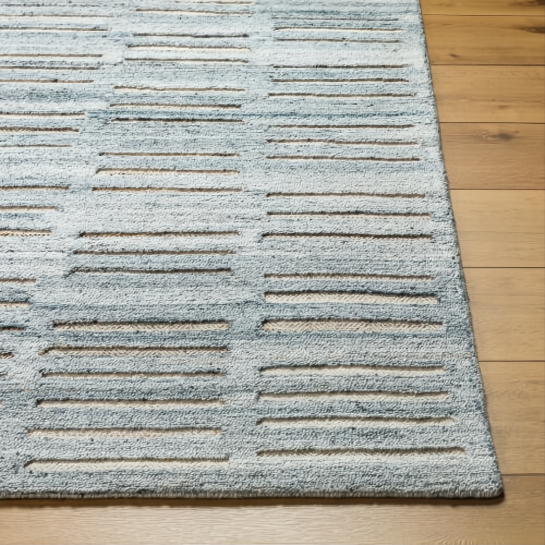 Surya Calgary CGR-2306-P hand-tufted rug with pale blue, dark blue, and light beige stripes on a wood floor.