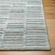 Surya Calgary CGR-2306-P hand-tufted rug with pale blue, dark blue, and light beige stripes on a wood floor.
