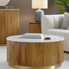 Round Surya Nems coffee table with white polished marble top, reeded brown mango wood base, and gold accents.