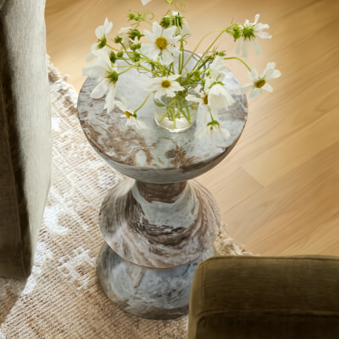 Surya Sheena 20"H brown marble end table with industrial rustic style, topped with white flowers.