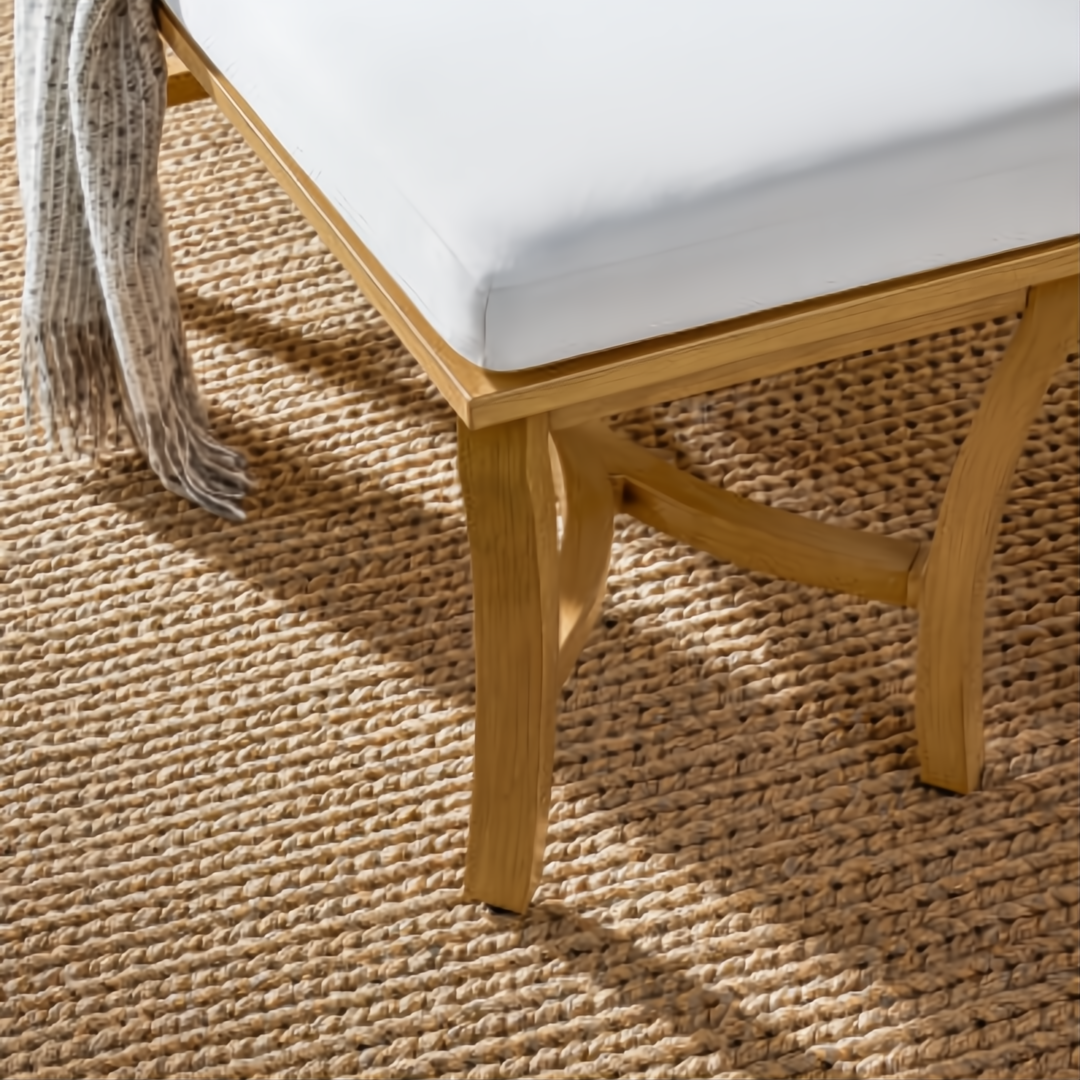 Surya Cape Town outdoor bench with wheat aluminum frame, white Sunbrella upholstery, and a woven rug.