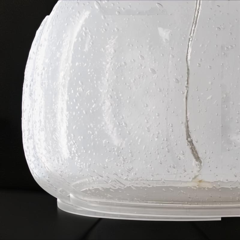 Close-up of Surya Bentley accent table lamp base, featuring clear seeded glass on a black surface.