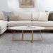 Surya Akola oval coffee table with white natural marble top and gold powder-coated iron base in a living room.