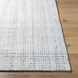 Surya Hope hand-loomed flatwoven rug in white, gray, and light slate recycled PET yarn on wood floor.