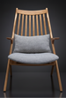 Mid-century modern accent chair with light wood frame and gray upholstered seat and lumbar pillow.